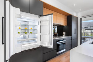 Interior photo of kitchen with open french door refrigerator, modern minimalist cabinets and gas range cook top