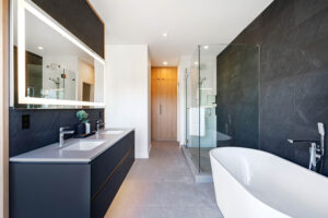 Master ensuite bathroom with floating vanity feature wall, stand alone porcelain bathtub, glass enclosed shower and walk-in closet