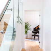 Picture of view from front entry door into main floor flex room with baby grand piano and large plant in a ceramic pot