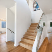 Picture of central staircase with wood flooring to contrast walls and metal railings with clear glass
